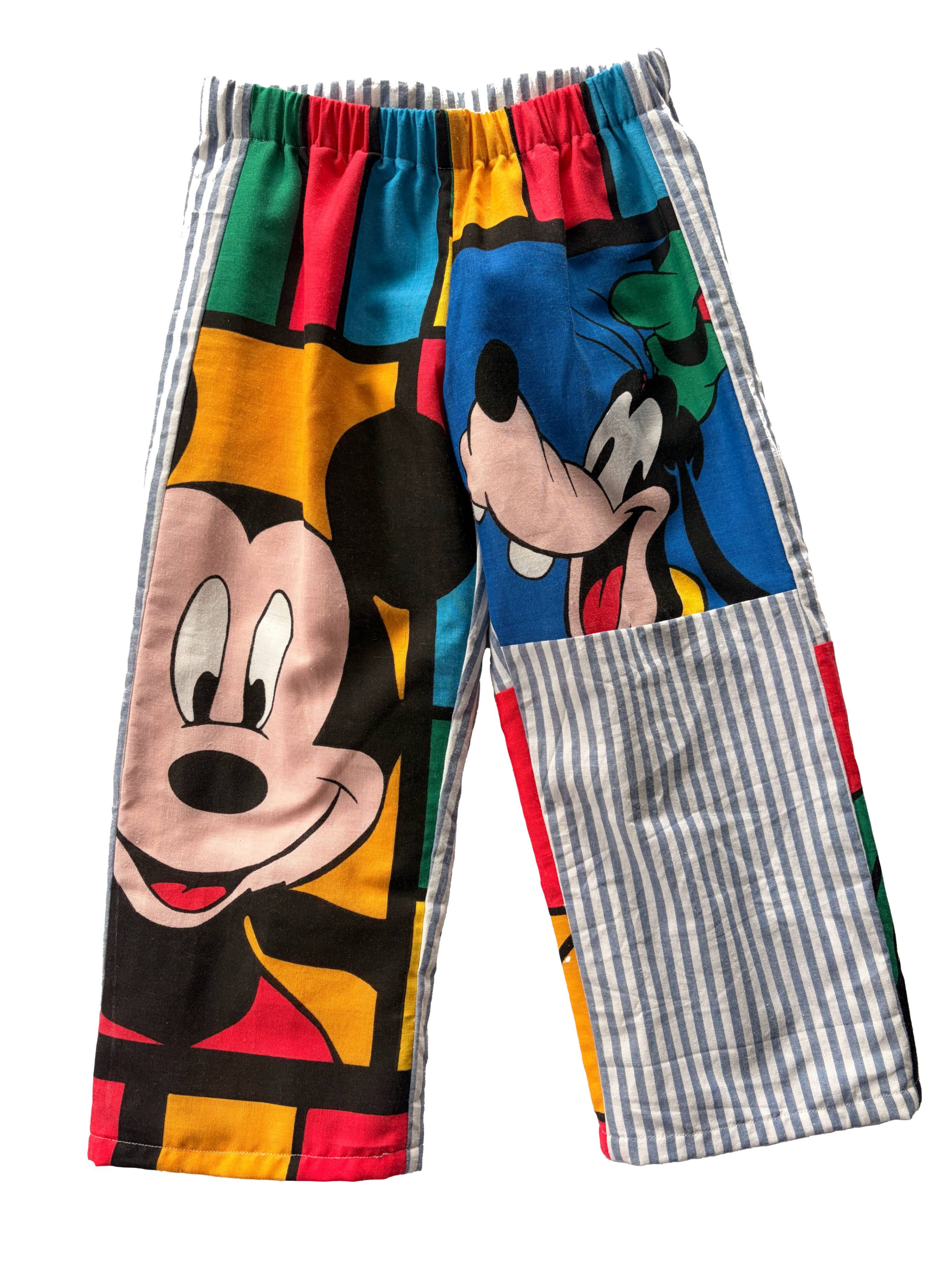 A pair of children's shorts featuring a colourful cartoon print of Mickey Mouse and Goofy, with blue and white striped leg, shown against a plain white background.